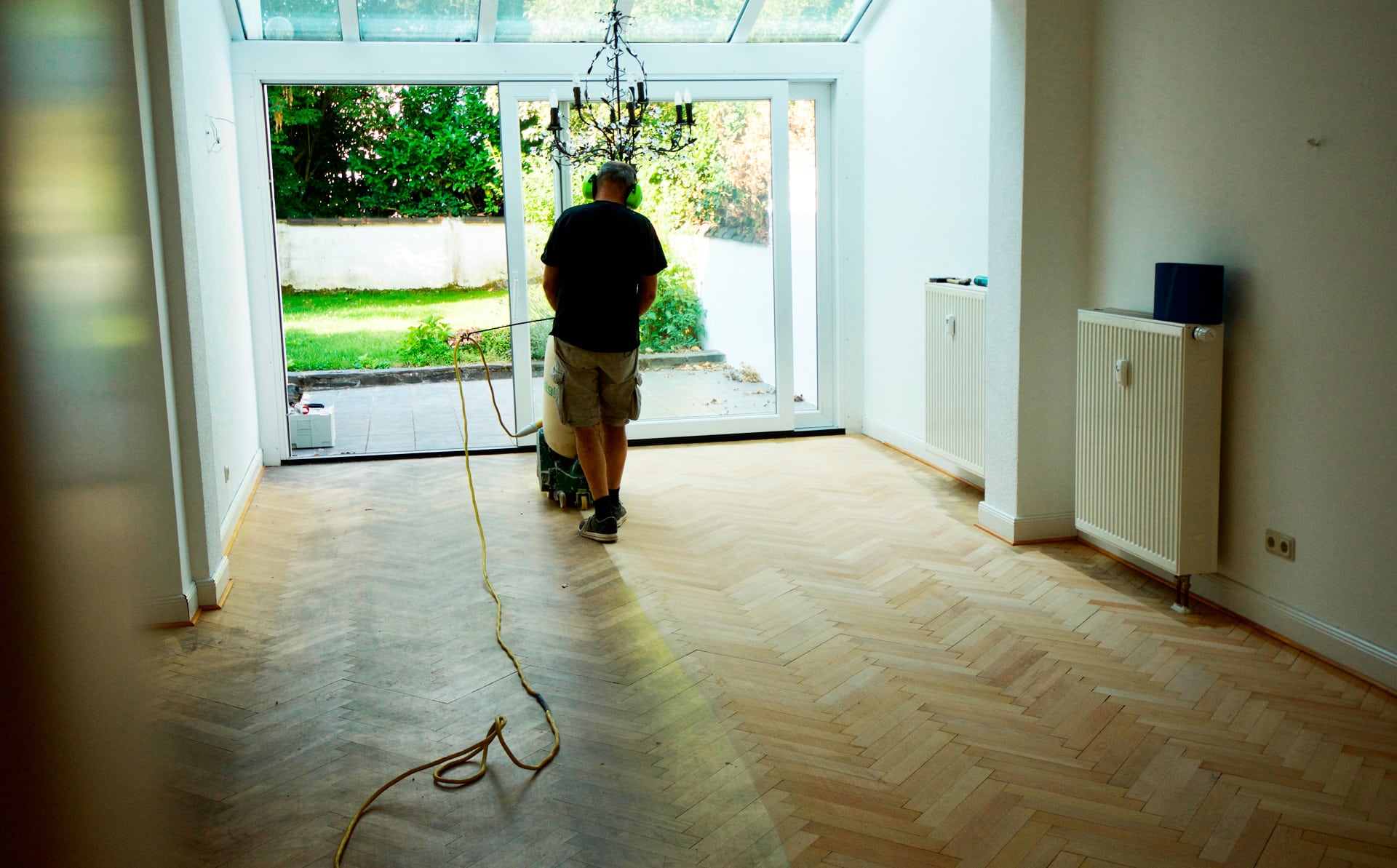Ein Mann arbeitet an einem Holzboden in einem Raum mit Referenzen. Raumausstattung Merget | Goethestraße 43 | 63814 Mainaschaff